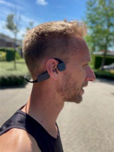Mann som l&oslash;per med hodetelefoner med benledning