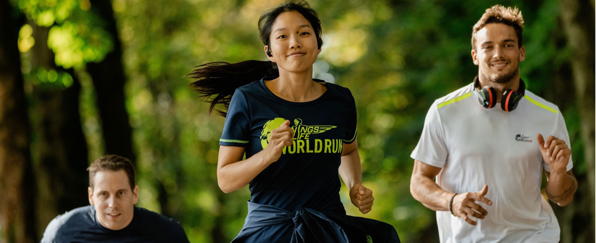 Tre Wings for Life World Run-deltakere løper med glede og bruker Philips-sportshodetelefoner.