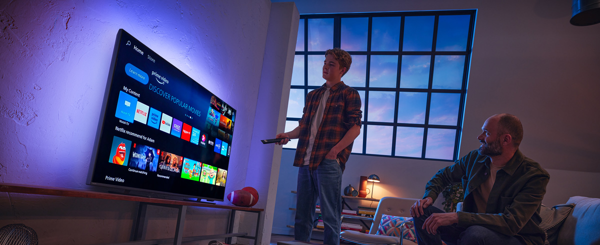 En mann som velger en app på en smart-TV fra Philips